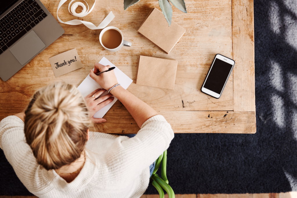 Overhead Shot Looking Down On Woman Writing In Generic Thank You Card