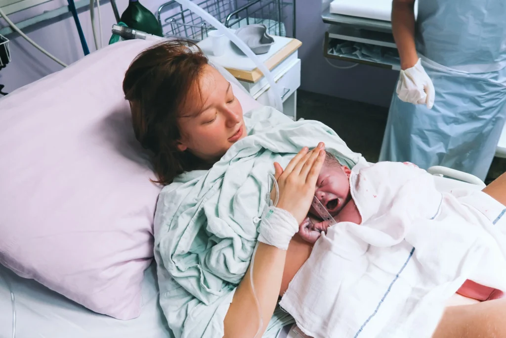 Mother holding her newborn baby child after labor in a hospital.